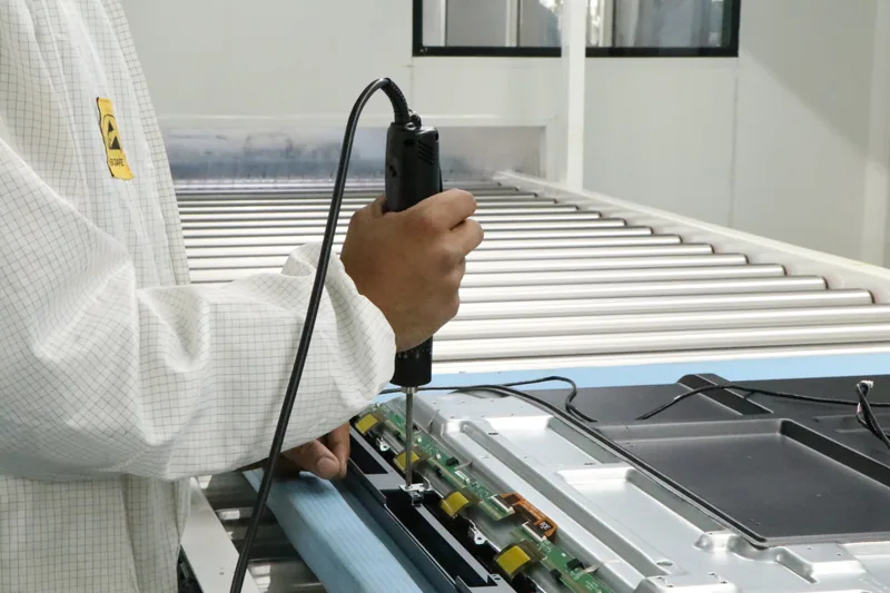 Technician precision-assembling a PCB display panel on SNL's IFP manufacturing line